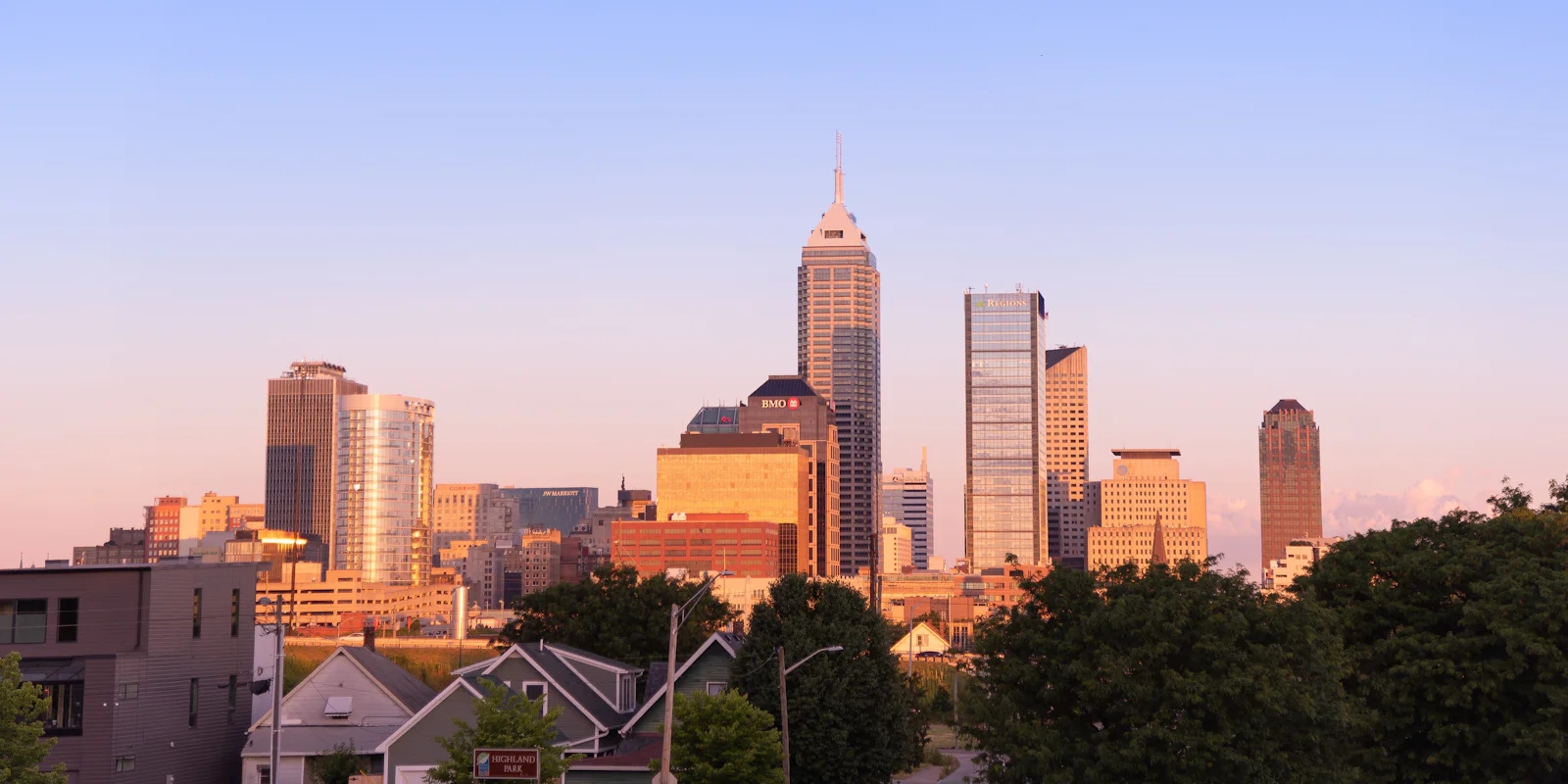 The Indianapolis skyline at dusk above trees and rooftops