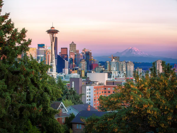 The Space Needle and downtown Seattle framed by trees, with Mount Rainier behind