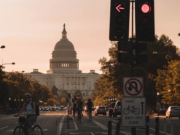 The US Capitol at the end of a street, with cyclists and traffic in warm evening light